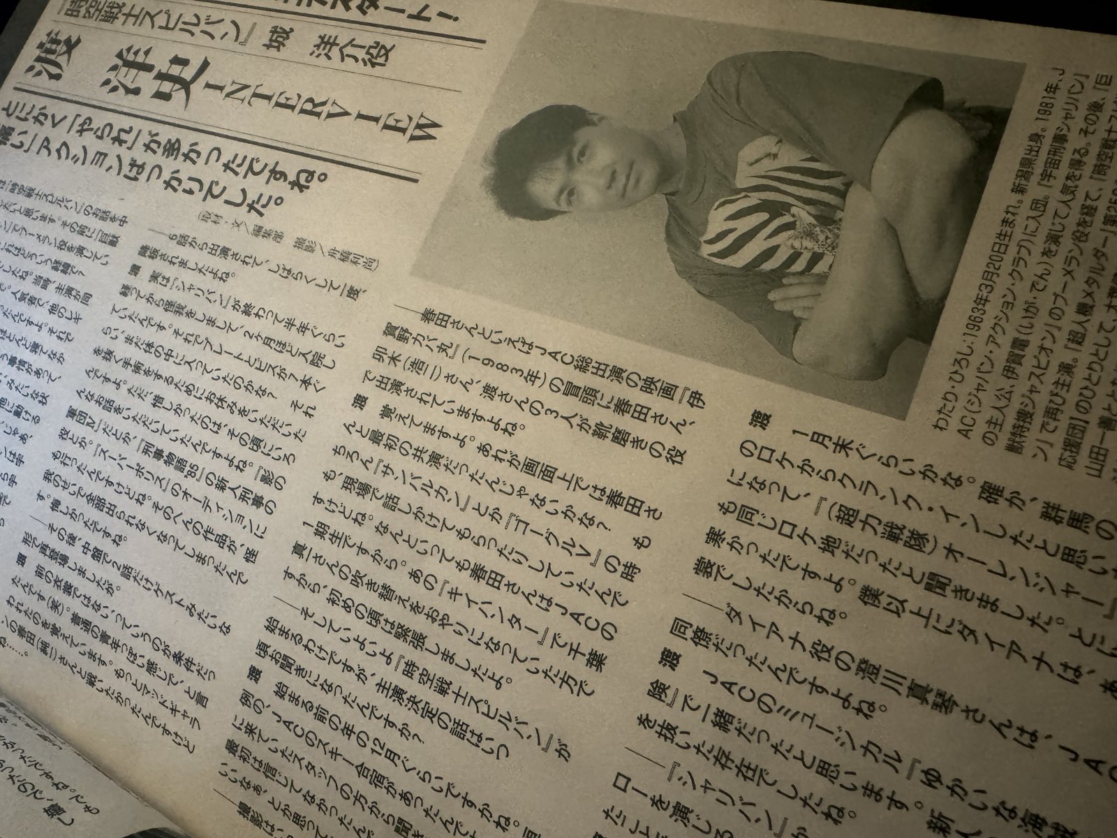 Página da revista Toei Hero Max de 2002 com a entrevista de Hiroshi Watari e uma foto dele sentado, de camiseta