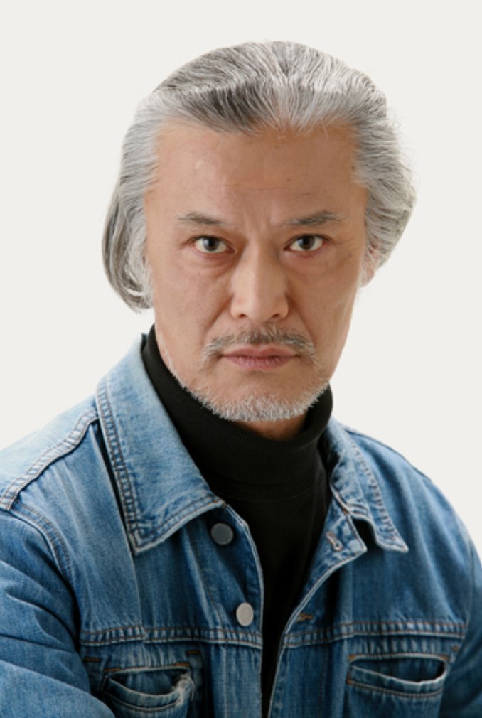 Kazuo Niibori, de cabelos grisalhos penteados para trás e jaqueta jeans, olha para a câmera