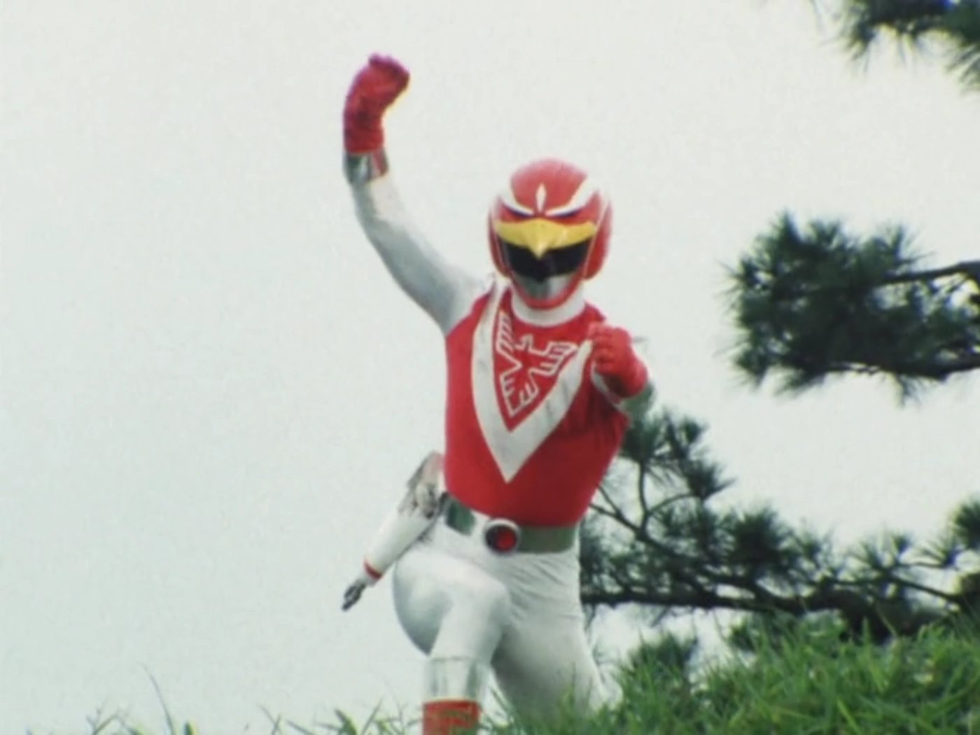 Red Falcon, de uniforme vermelho e branco com o desenho de um falcão no peito, ergue o punho ao ar livre