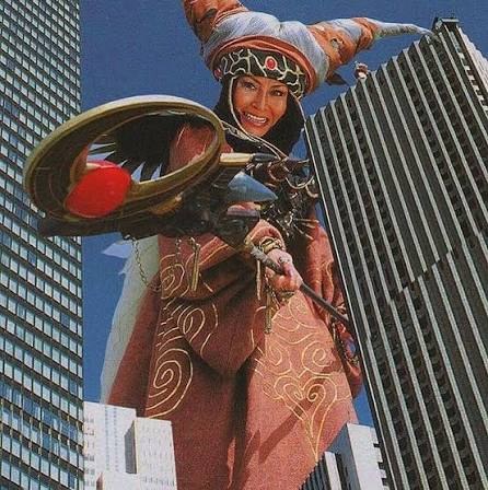 Bandora gigante entre dois arranha-céus, sorrindo e segurando o cetro