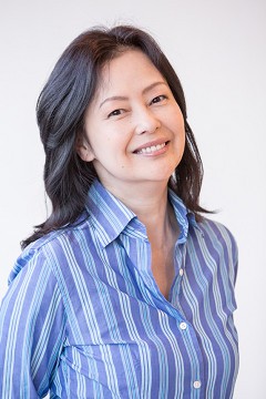 Portrait of a smiling Moyu Taguchi in a blue striped shirt against a white background