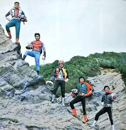 Five performers dressed as Riders pose on rocks, some holding the helmet