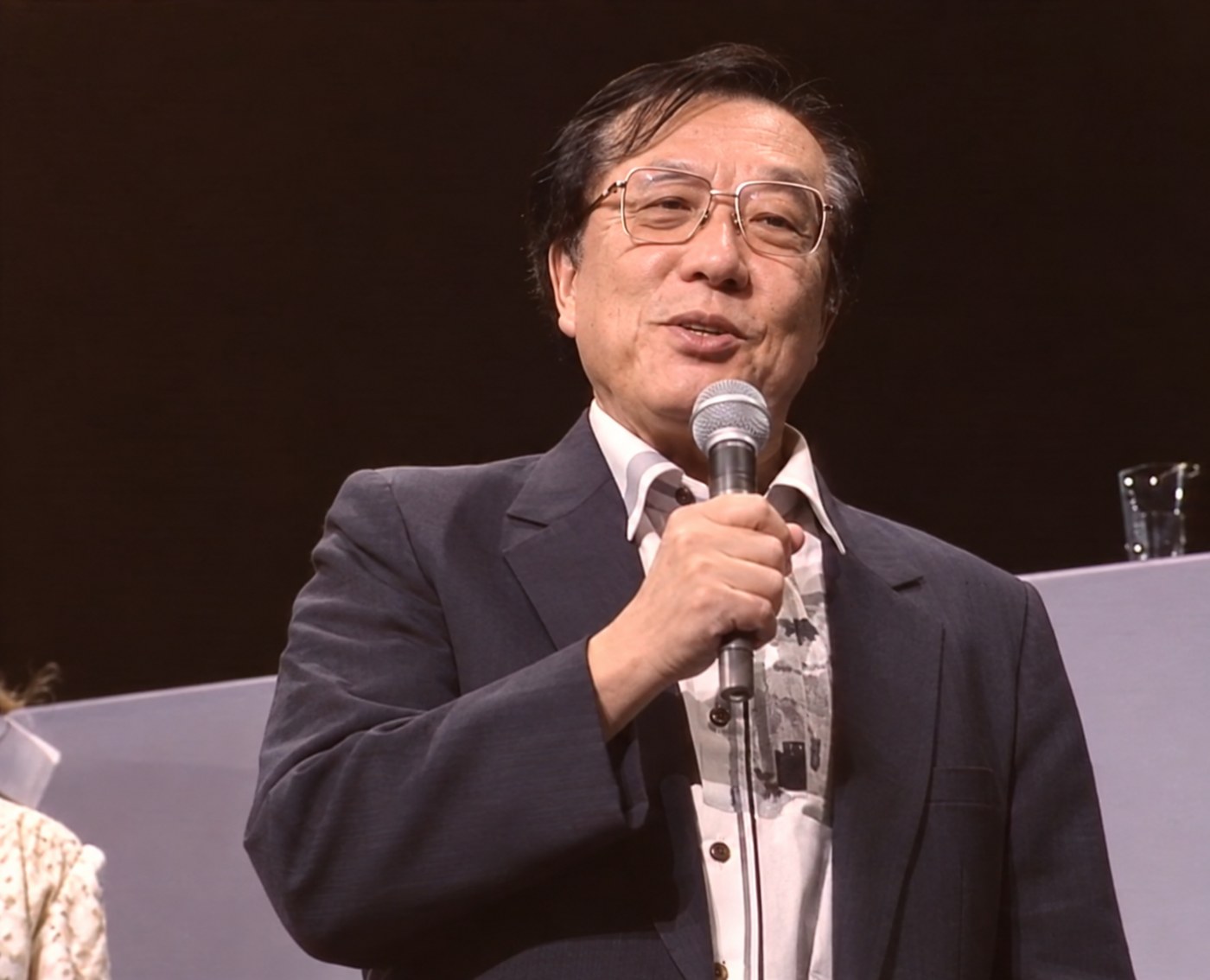 Composer Chumei Watanabe at the microphone at a tokusatsu event