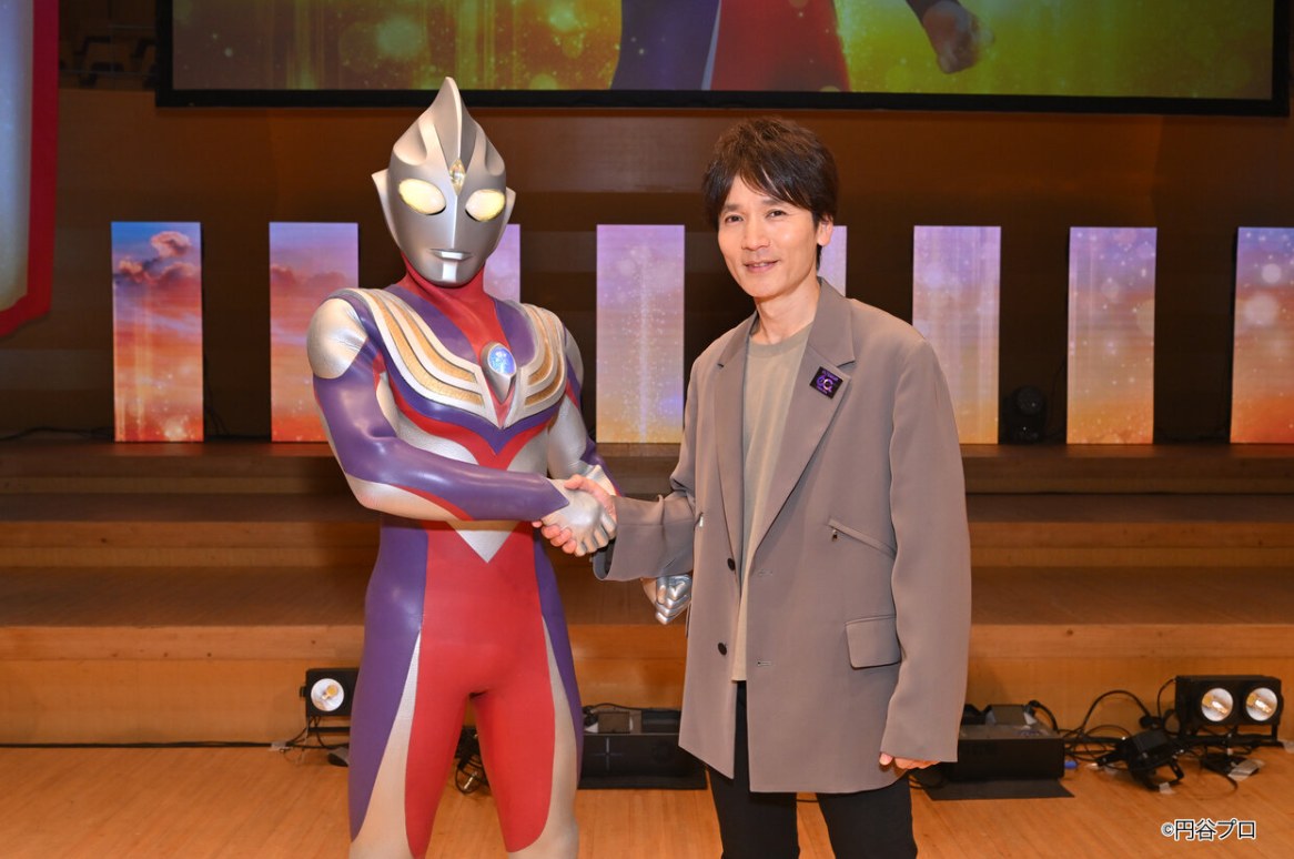 Hiroshi Nagano ao lado de Ultraman Tiga no palco do evento do Dia do Ultraman