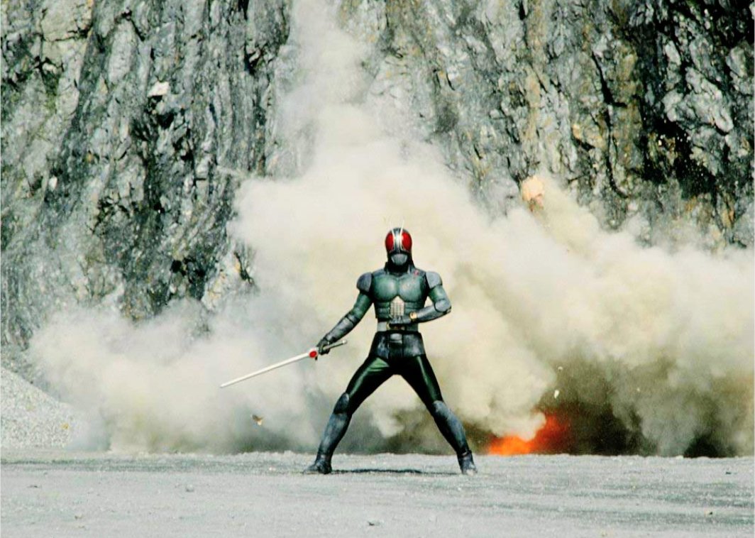 採石場で剣を手に爆発を背にする仮面ライダーBLACK