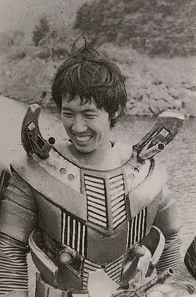 Osamu Kaneda jovem, sorrindo dentro de um traje de herói